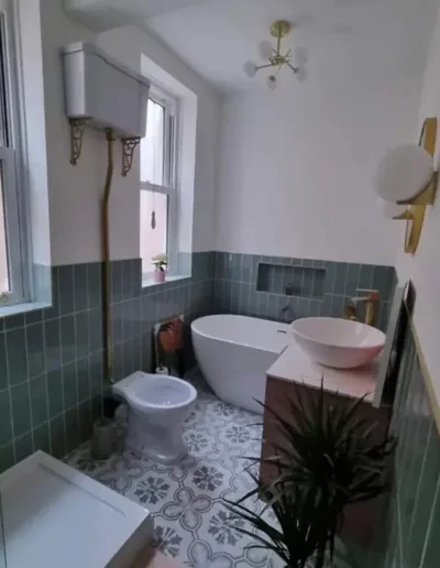 Renovated bathroom in Liverpool with green metro wall tiles, freestanding bath and patterned floor tiles