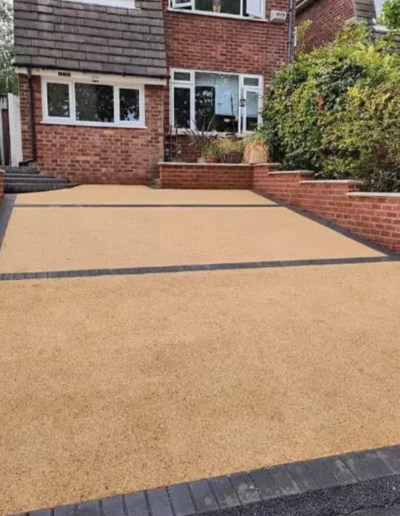 New resin-bound driveway installed in Liverpool with charcoal block paving border and brick retaining walls